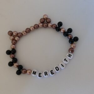 Brown beaded friendship bracelet in the shape of a cat head with ears and whiskers, with the name Meredith
