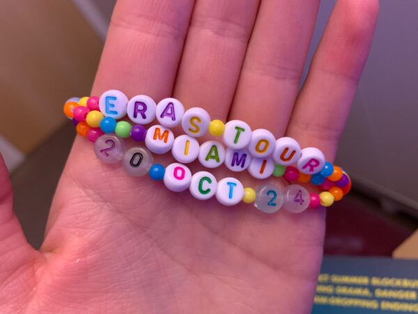 Rainbow friendship bracelet with clay and pearl beads with three strands reading Eras Tour, city, date