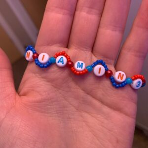 Friendship bracelet with small beads in a wavy pattern around the letters, with Eras Tour city and night number